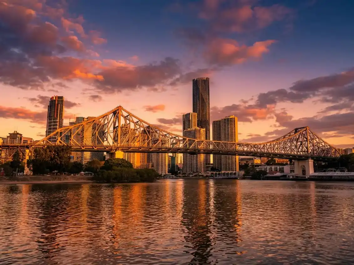 The iconic Brisbane Story Bridge at sunset with city skyscrapers reflecting in the river, representing the urban heart of the Sunny Link™ premium Brisbane collection.