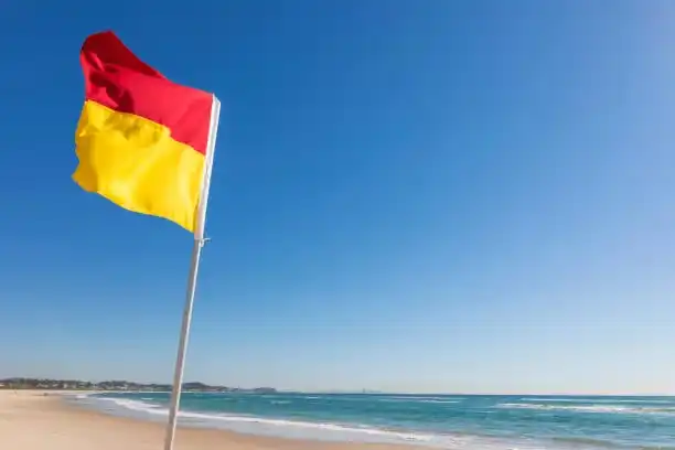 Iconic red and yellow patrol flags on a Gold Coast beach; Sunny Link™ encourages users to stay within patrolled areas while using the app to find local gems.